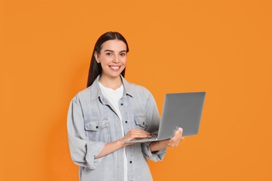 Photo of Happy woman with laptop on orange background
