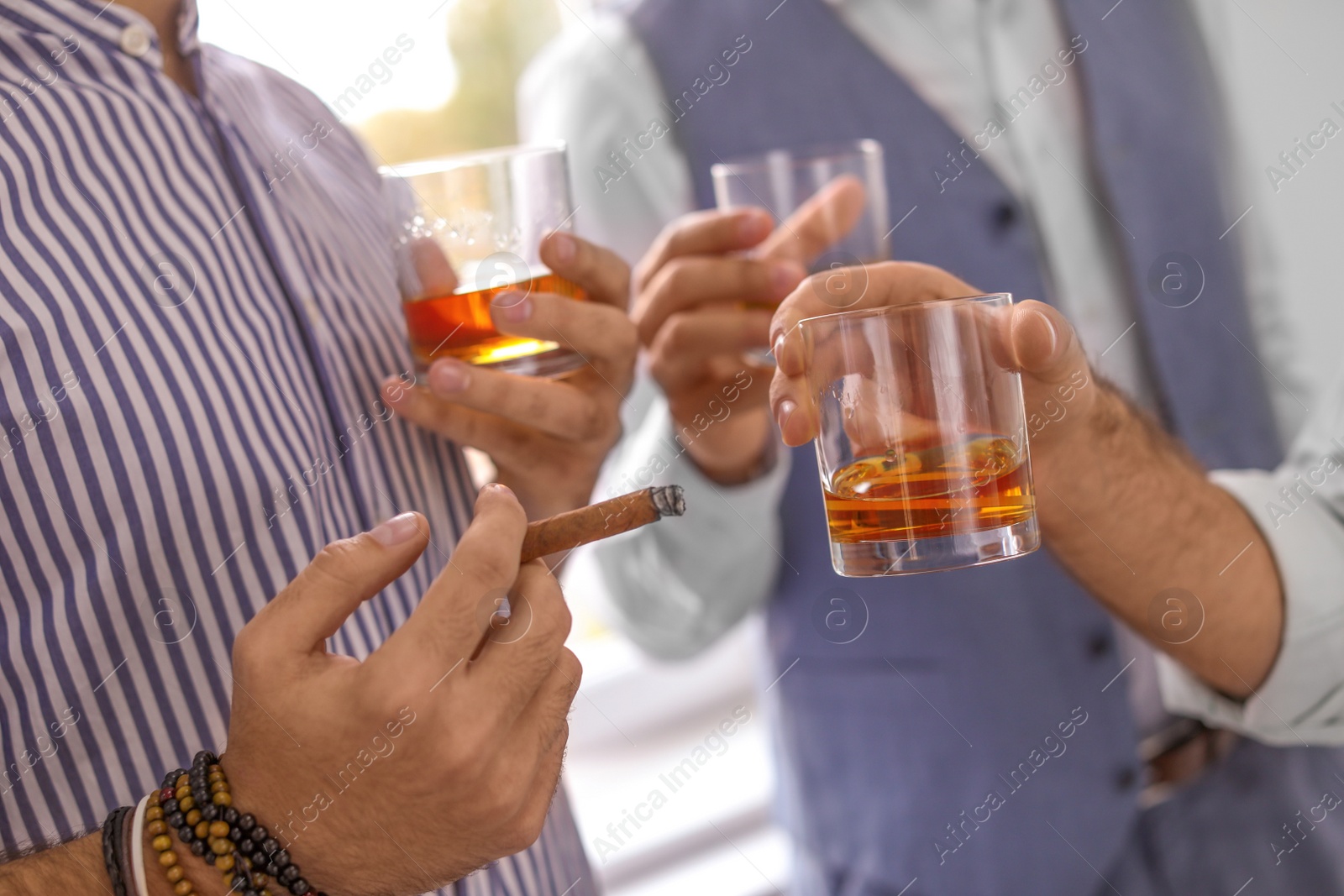 Photo of Group of friends drinking whiskey together indoors, closeup