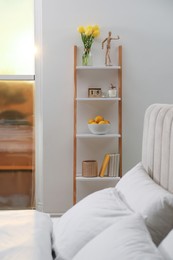 Photo of Stylish bedroom interior with wooden ladder near white wall