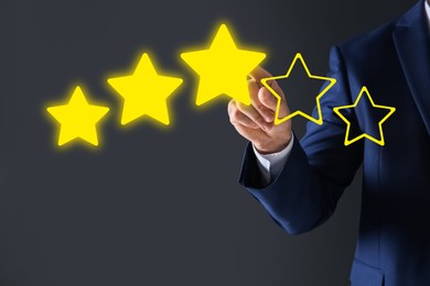 Image of Man pointing at icons of stars on grey background, closeup. Quality rating