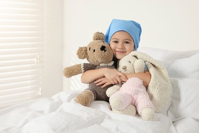 Photo of Childhood cancer. Girl hugging toy bunny and bear in hospital