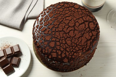 Photo of Delicious truffle cake and chocolate pieces on light wooden table, above view