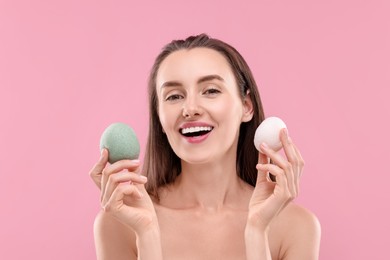 Photo of Happy young woman holding face sponges on pink background