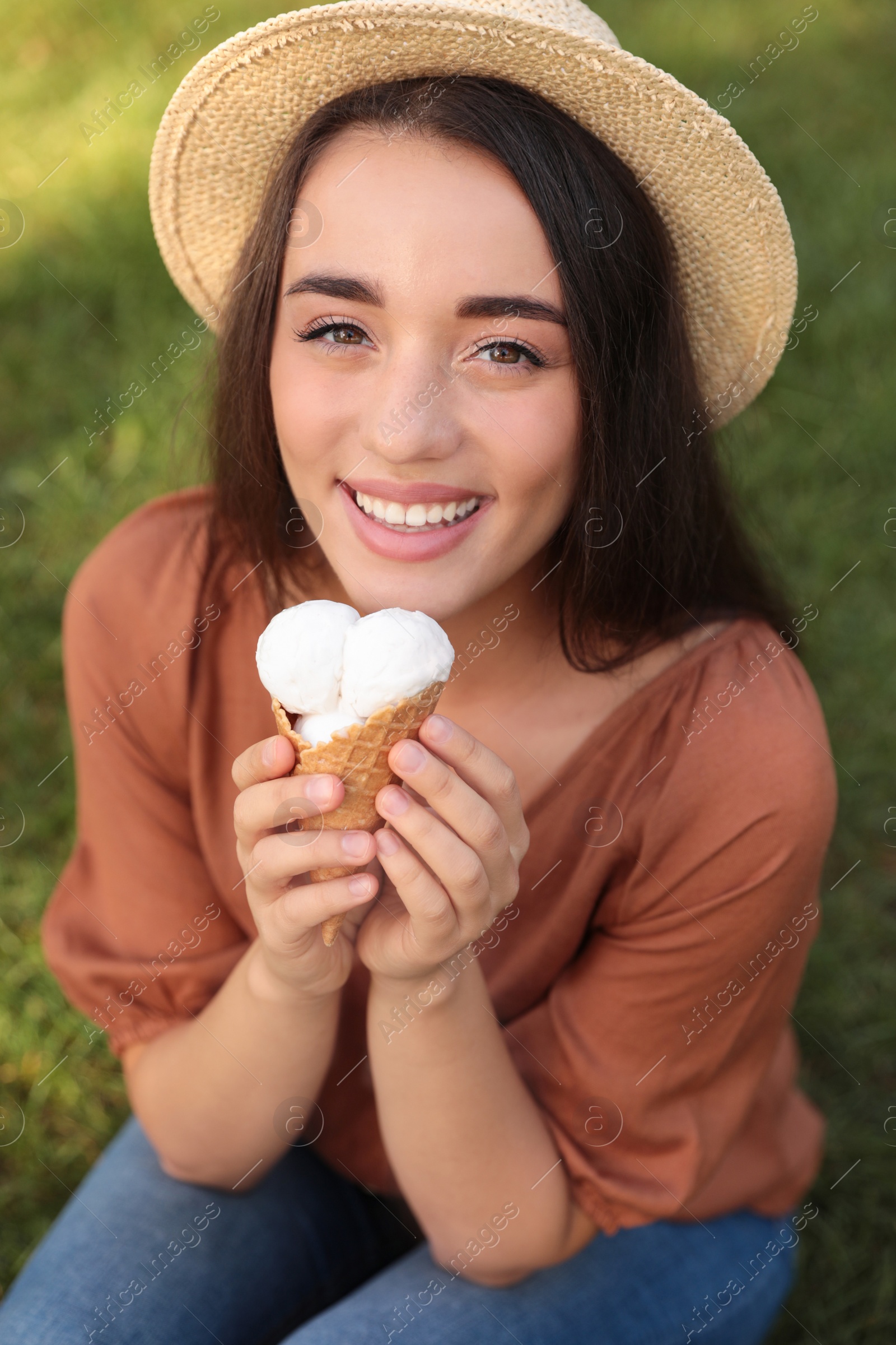 Photo of Happy young woman with delicious ice cream in waffle cone outdoors