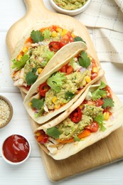 Delicious tacos with guacamole, meat and vegetables served on white wooden table, flat lay