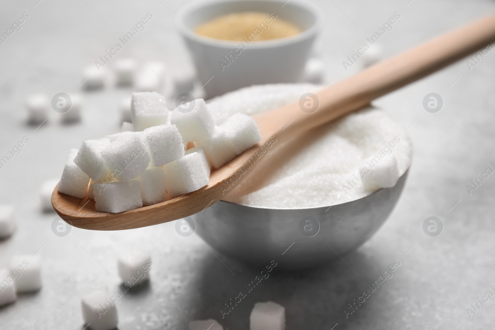 Photo of Spoon and bowl with white sugar on gray background