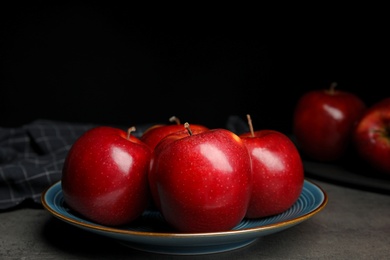 Plate with ripe juicy red apples on grey table