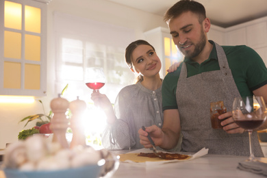 Lovely young couple cooking pizza together in kitchen