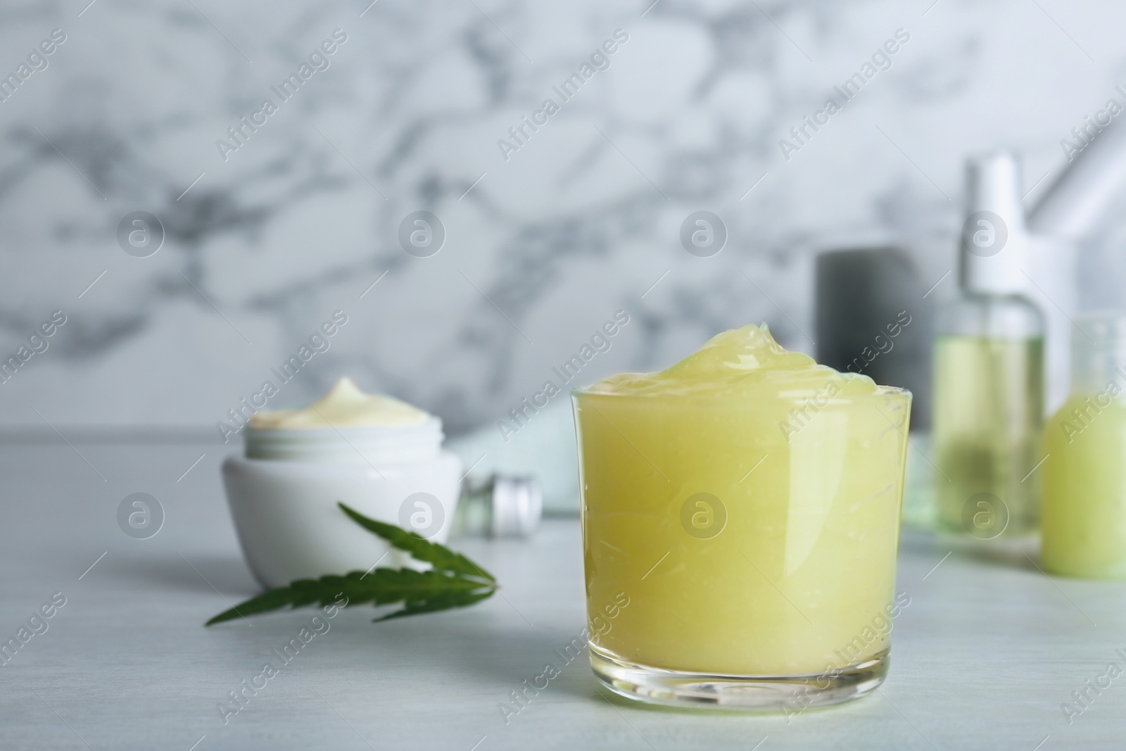 Photo of Glass of moisturizing hemp lotion on table