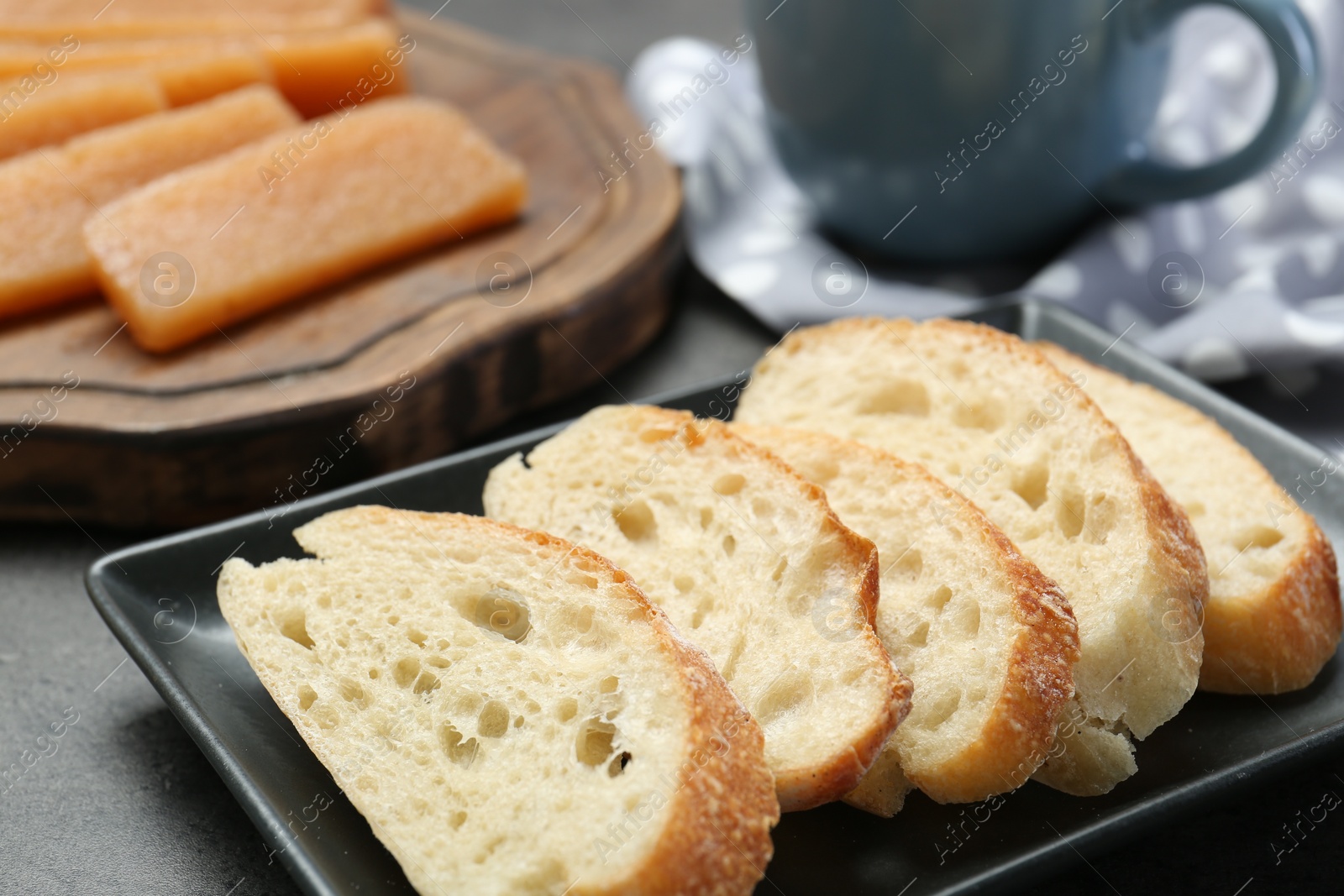 Photo of Delicious quince paste and bread on grey textured table, closeup