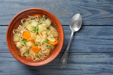 Bowl of fresh homemade vegetable soup served on blue wooden table, flat lay. Space for text