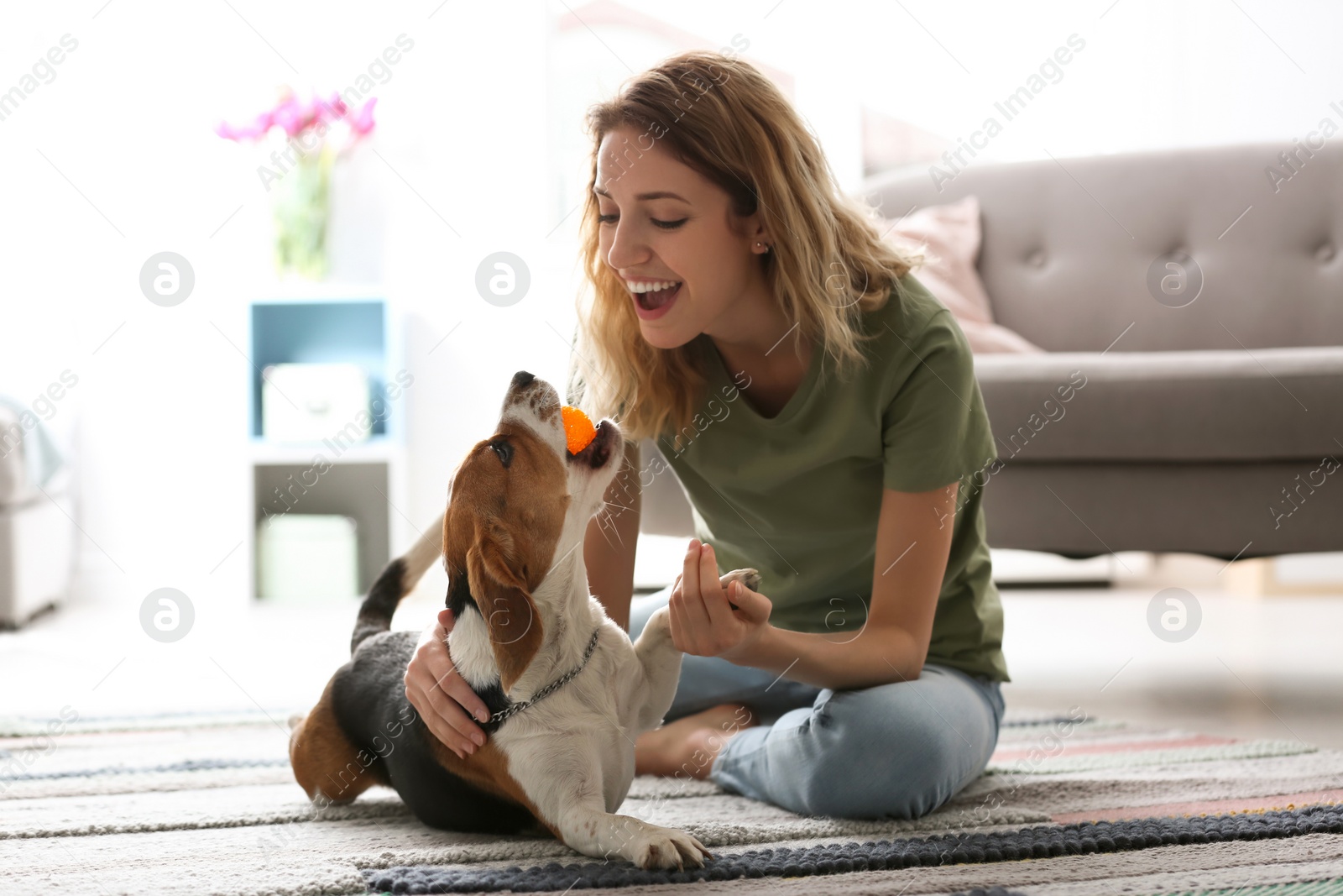 Photo of Young woman playing with her dog at home