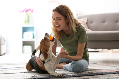 Photo of Young woman playing with her dog at home