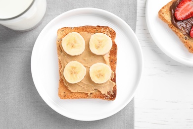 Photo of Flat lay composition of toast with peanut butter on white wooden table. Healthy breakfast