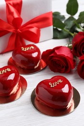 Photo of St. Valentine's Day. Delicious heart shaped cakes, roses and gift on white wooden table
