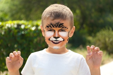 Photo of Cute little boy with face painting outdoors