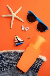 Flat lay composition with bottle of sunscreen on coral background