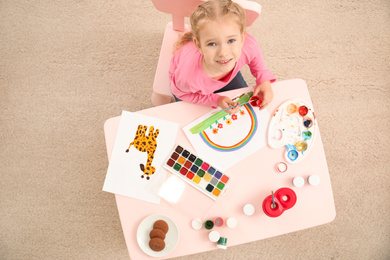 Cute little child painting at table, top view