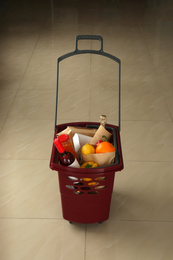 Shopping basket full of different products on beige tile floor