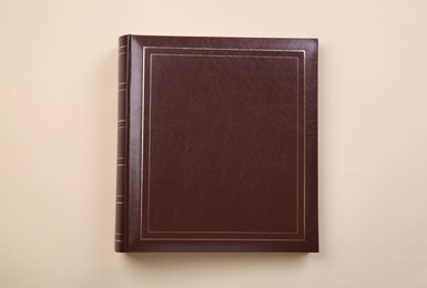 Photo of Photo album with leather cover on beige background, top view