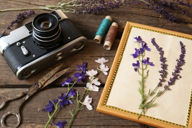 Photo of Composition with beautiful dried flowers, vintage camera and photo frame on wooden table