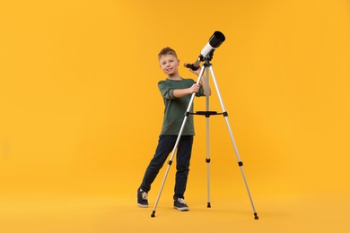 Photo of Happy little boy with telescope on orange background