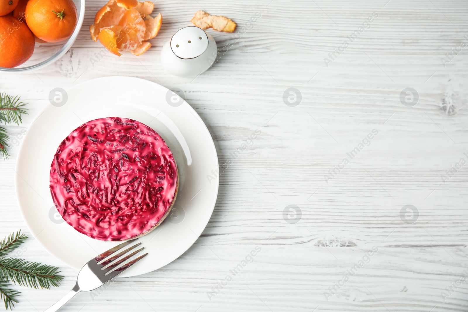 Photo of Flat lay composition with herring under fur coat, tangerines and fir branches on white wooden table, space for text. Traditional russian salad