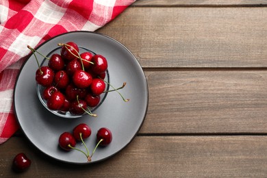 Photo of Wet red cherries on wooden table, flat lay. Space for text