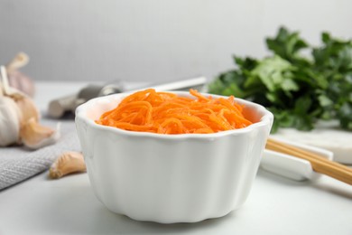 Photo of Delicious Korean carrot salad in bowl on white table