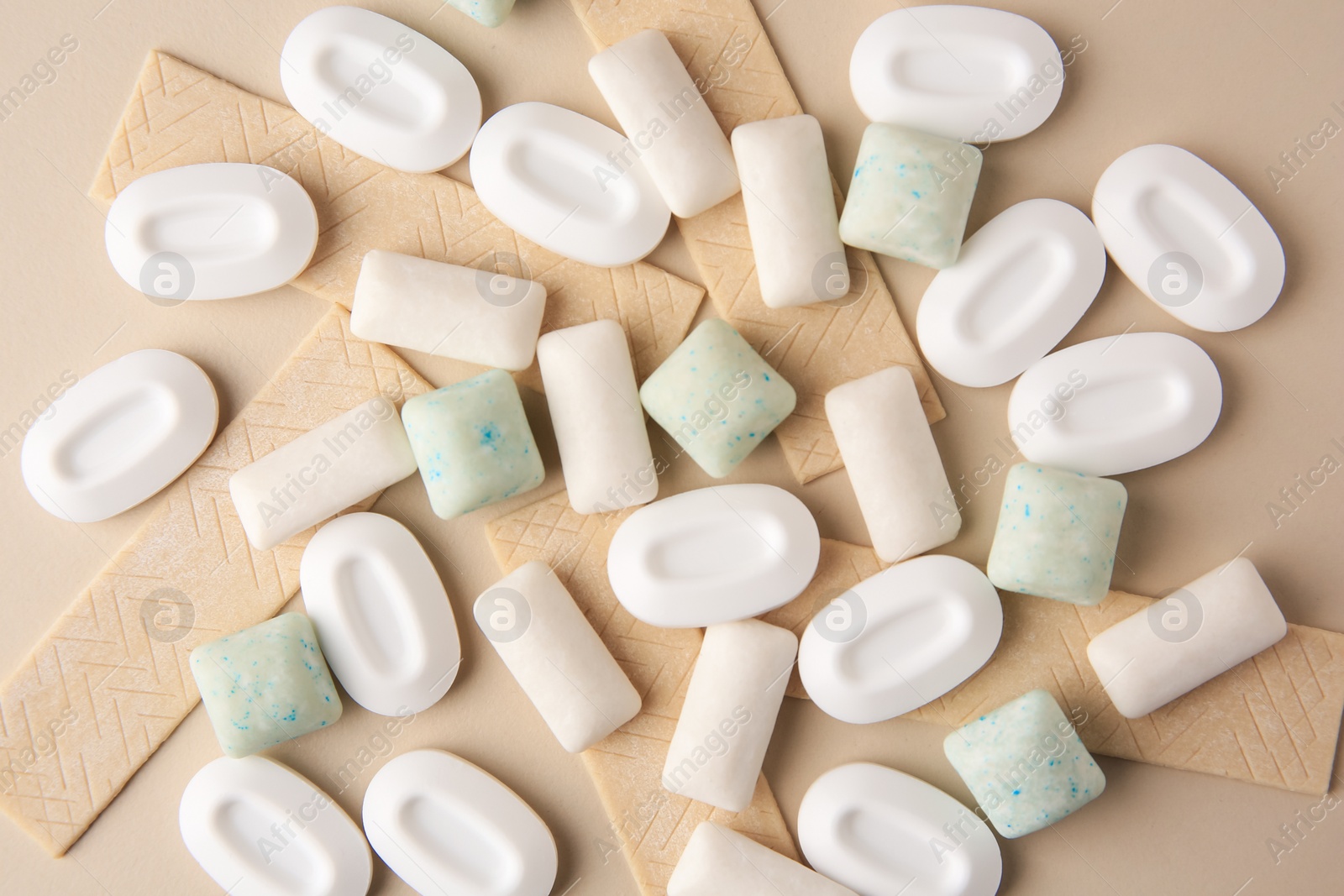 Photo of Many different chewing gums on beige background, flat lay