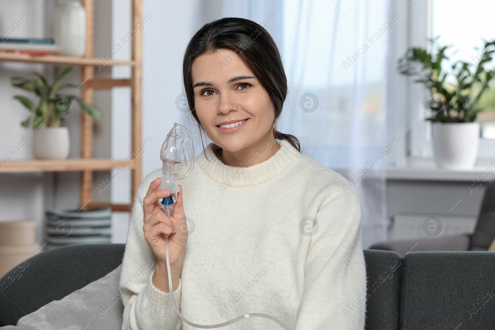 Photo of Happy young woman with nebulizer at home