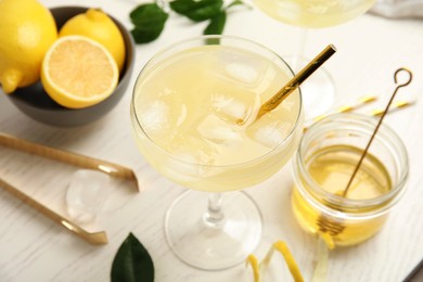 Photo of Delicious bee's knees cocktail and ingredients on white wooden table