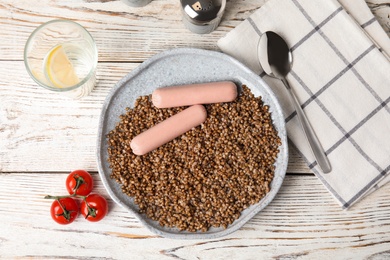 Flat lay composition with tasty buckwheat porridge and sausages on white wooden table