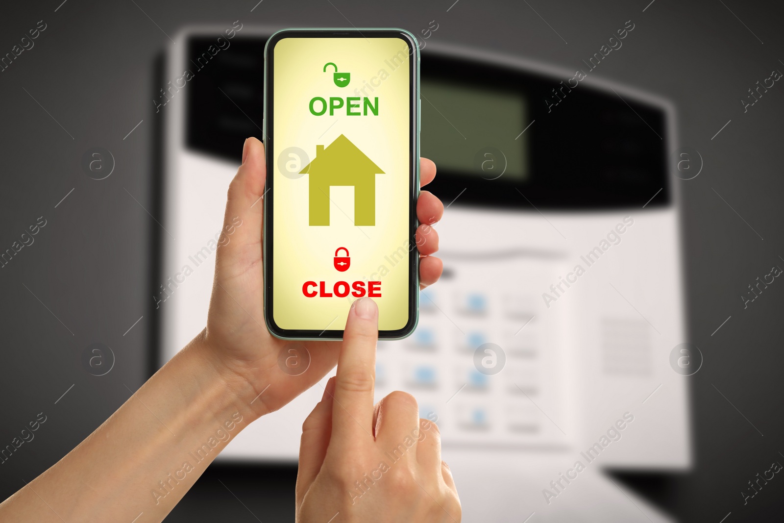 Image of Woman operating home alarm system via mobile phone against dark wall with security control panel, closeup. Application interface on device screen