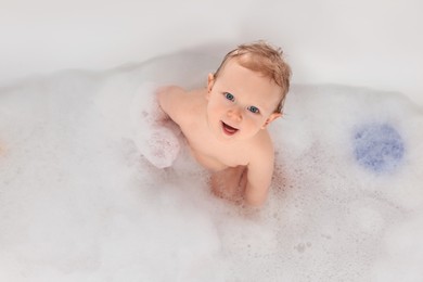 Photo of Cute little baby bathing in tub at home, top view