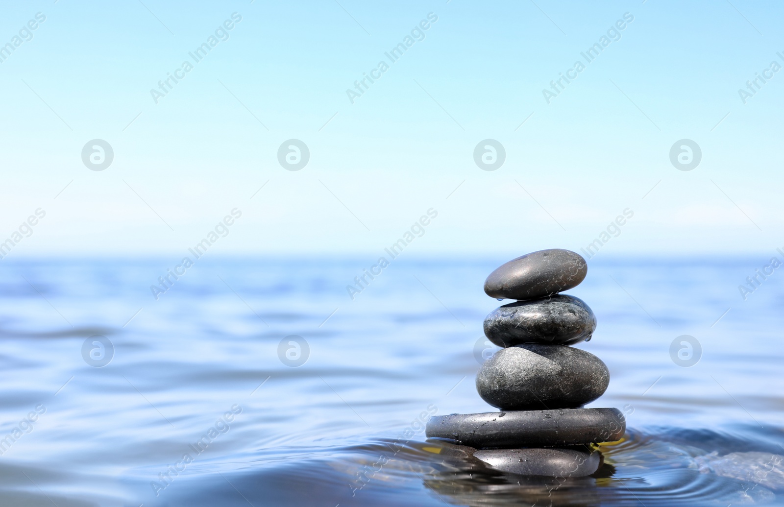 Photo of Stack of stones in sea water, space for text. Zen concept