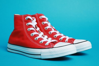 Pair of new stylish red sneakers on light blue background