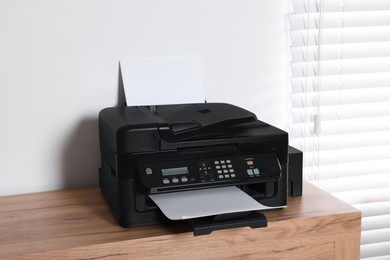 Modern printer with paper on wooden table indoors