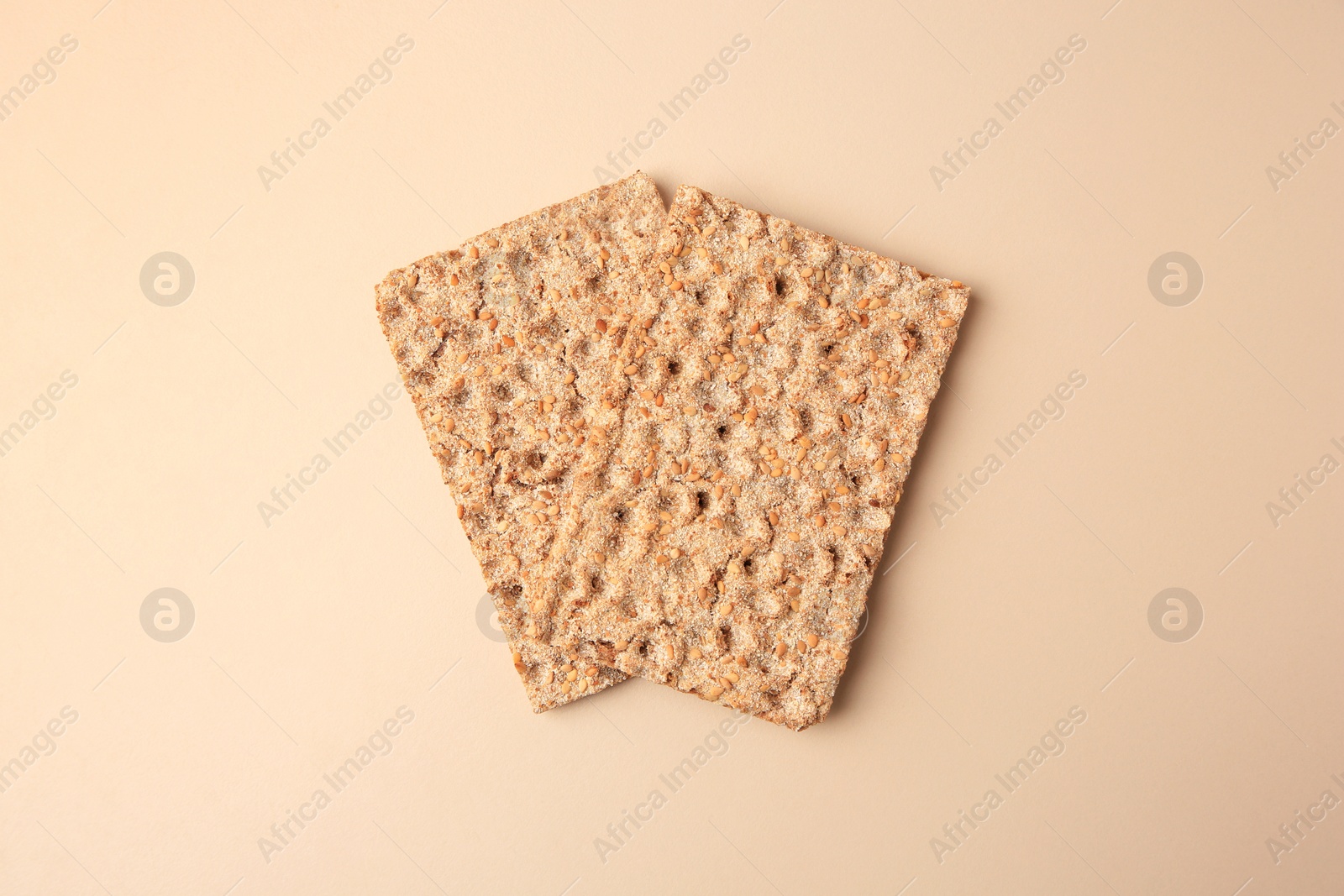 Photo of Fresh crunchy crispbreads on beige background, flat lay