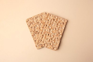 Photo of Fresh crunchy crispbreads on beige background, flat lay