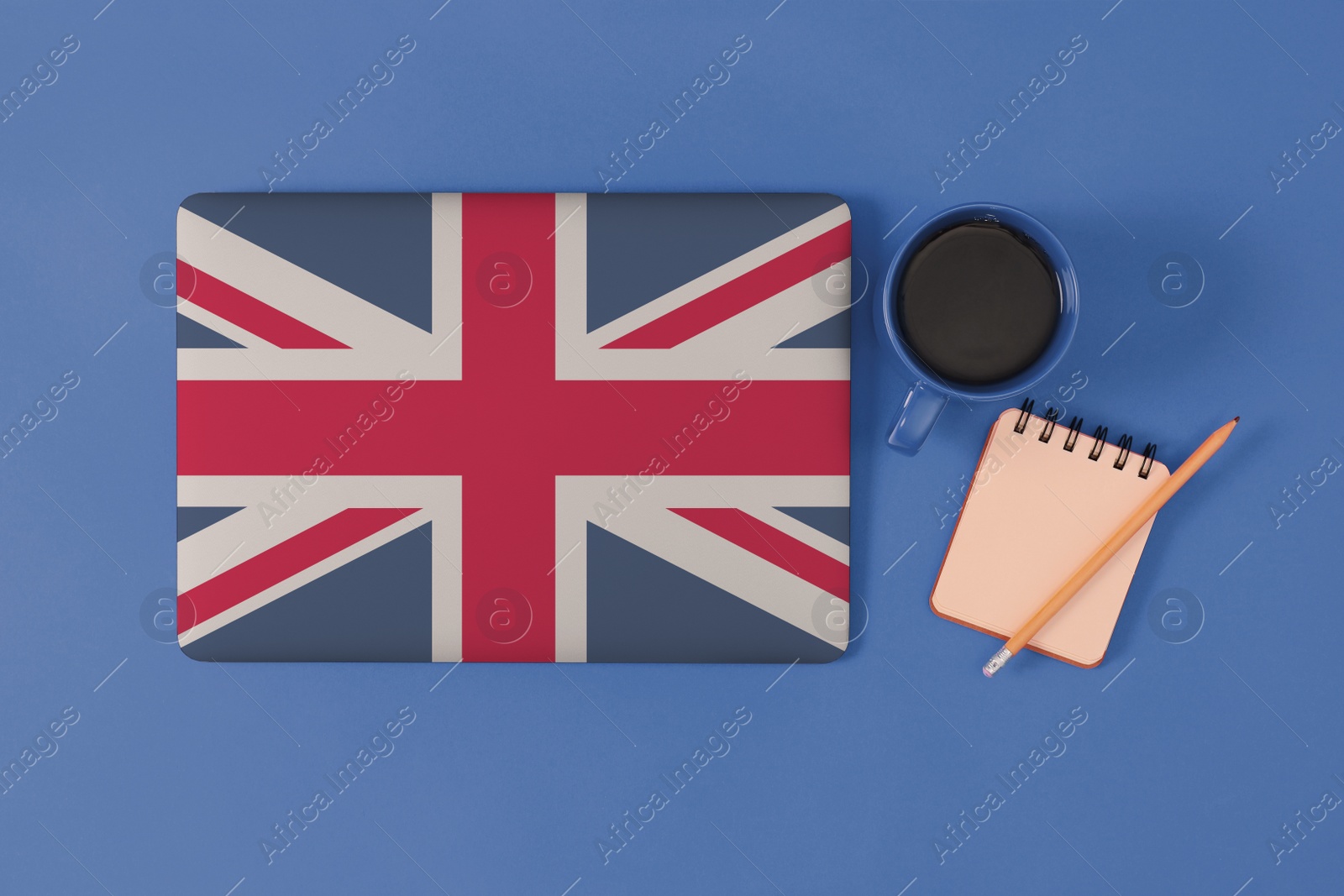 Image of Modern laptop with cup of coffee and stationery on blue background, flat lay. Learning English