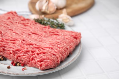 Fresh raw ground meat and peppercorns on white tiled table, closeup. Space for text