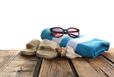 Towel, sunglasses, shoes and sea shell on wooden table. Beach accessories