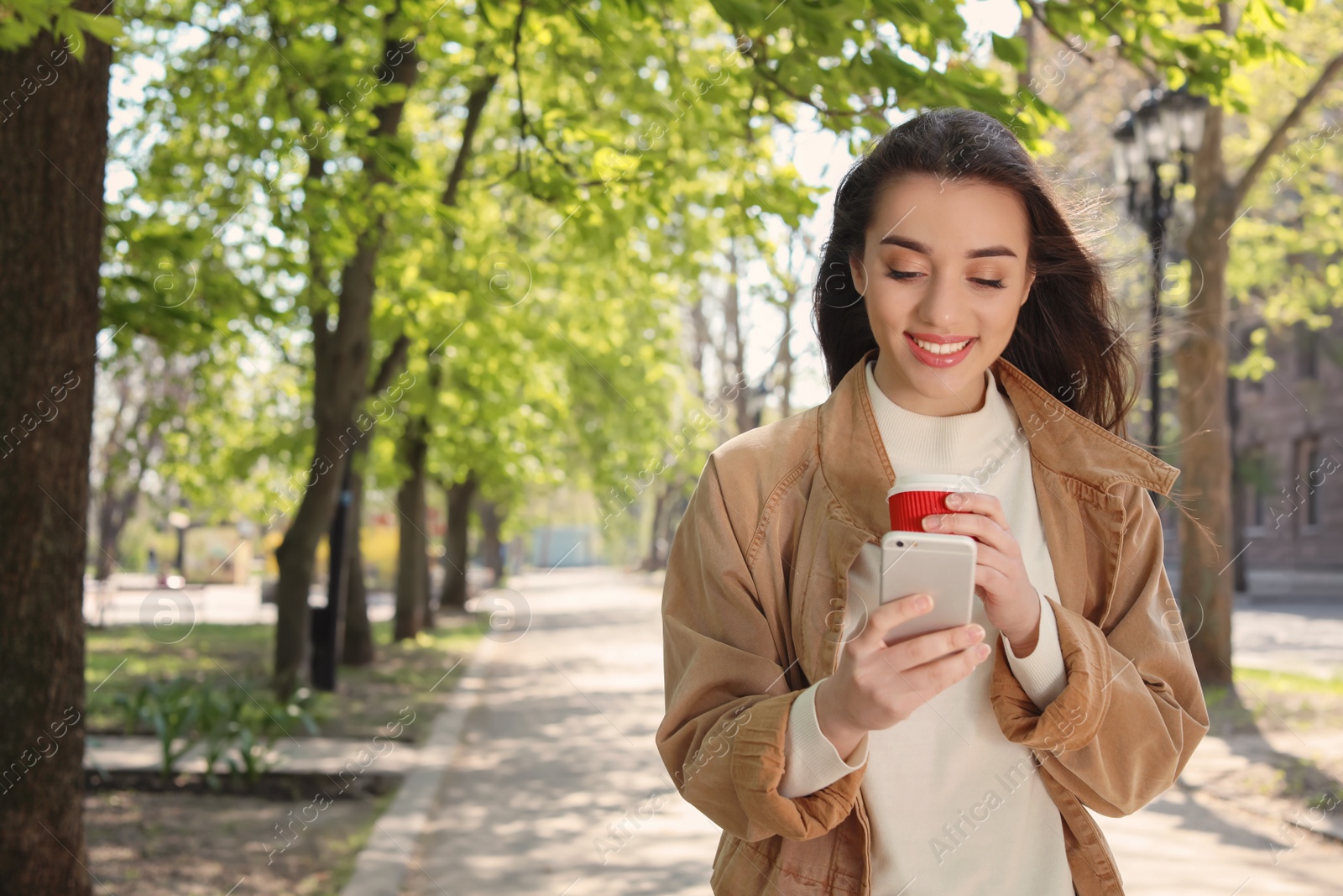 Photo of Young woman using phone outdoors on sunny day