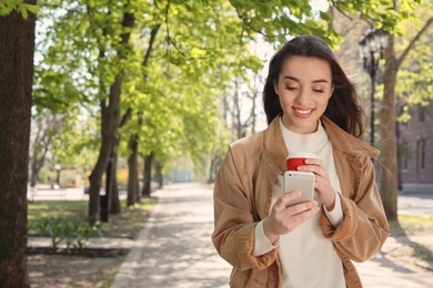 Young woman using phone outdoors on sunny day