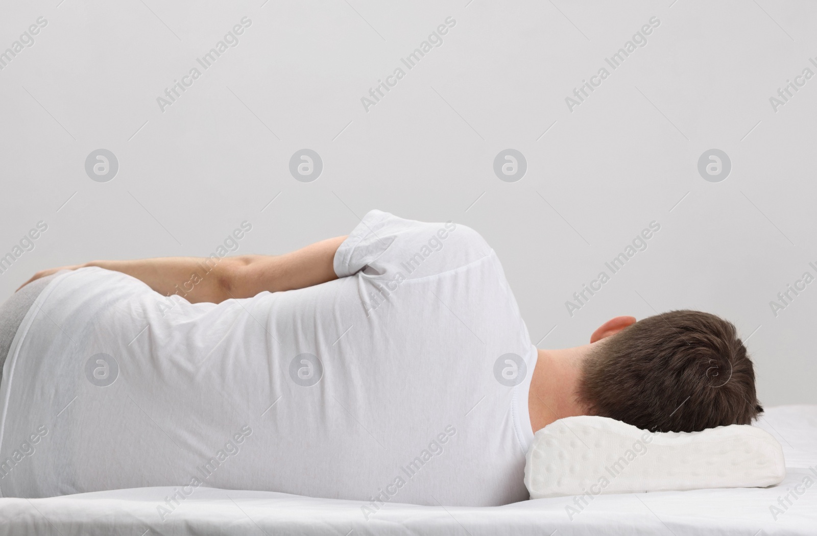 Photo of Man sleeping on orthopedic pillow against light grey background