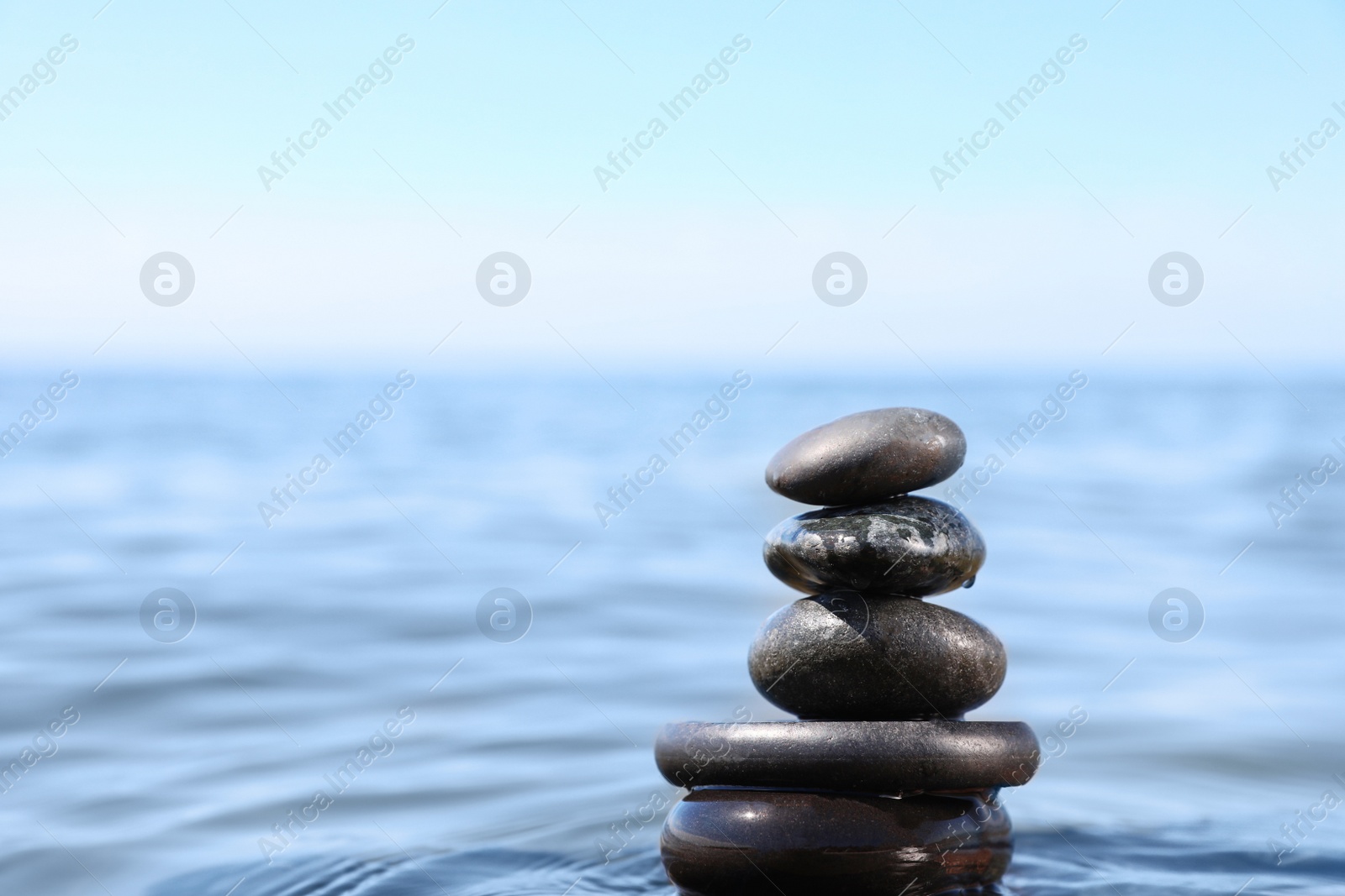 Photo of Stack of stones in sea water, space for text. Zen concept