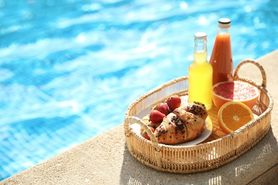Photo of Tray with delicious breakfast near swimming pool. Space for text
