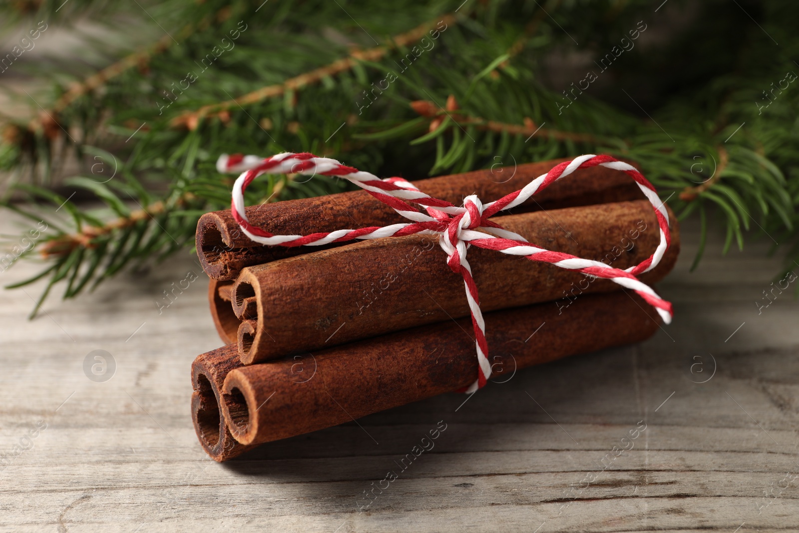 Photo of Cinnamon sticks and fir branches on wooden table, closeup