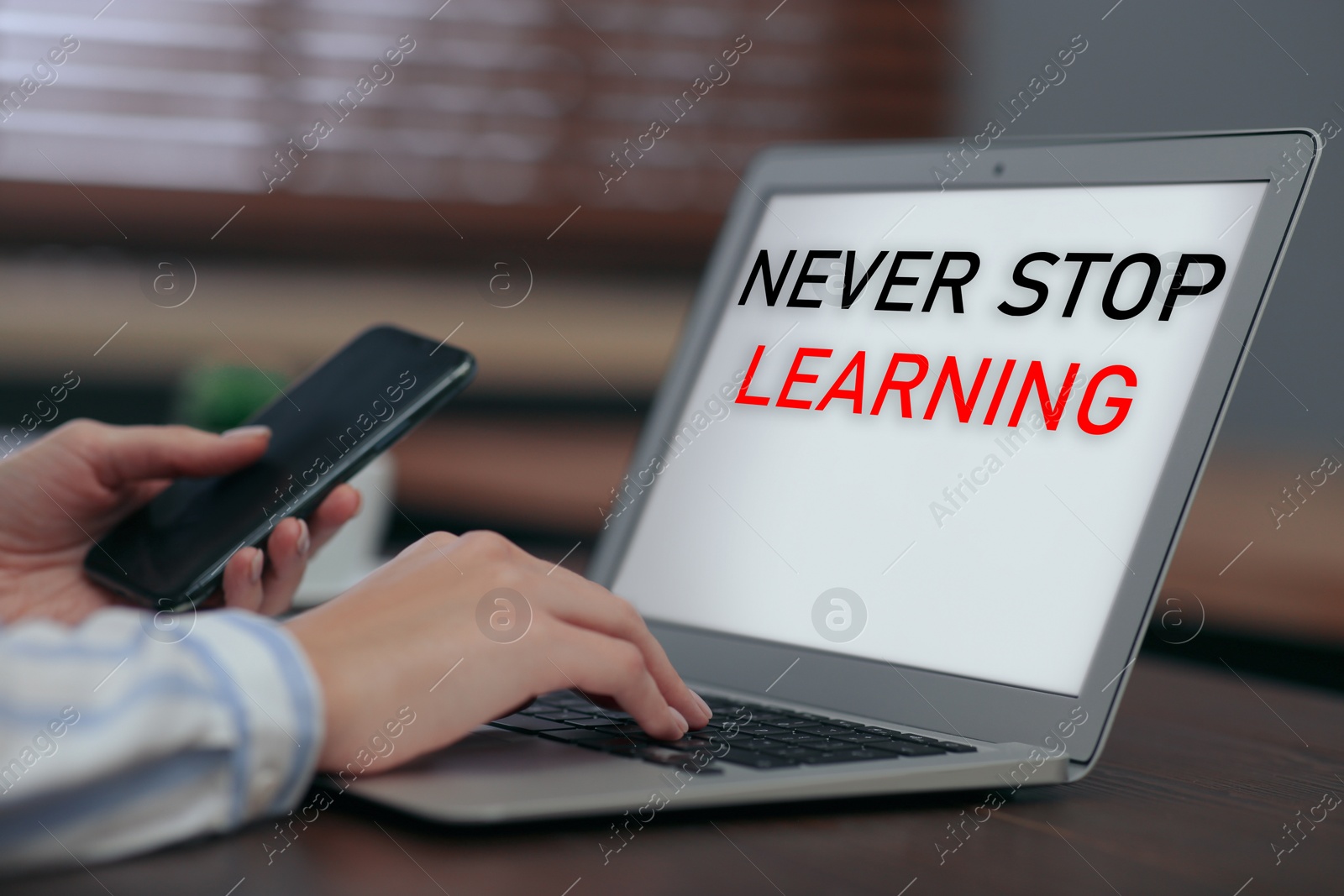 Image of Woman with phone working on laptop at table indoors, closeup. Never stop learning